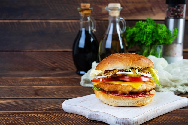 Tasty chicken burger with lettuce cheese tomato and pickle Fast food sandwich with chicken cutlet