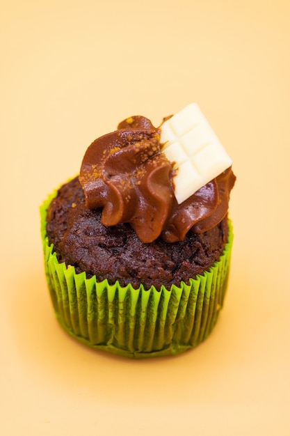 Tasty chocolate cupcake on orange pastel color background.