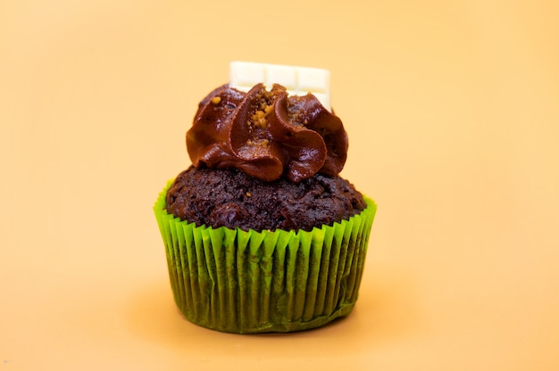 Tasty chocolate cupcake on orange pastel color background.