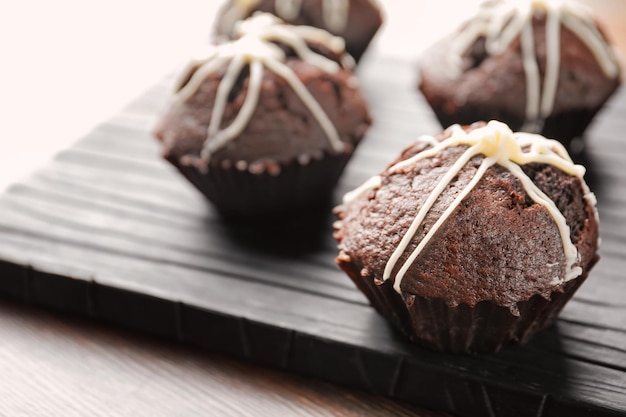 Photo tasty chocolate cupcakes on wooden board