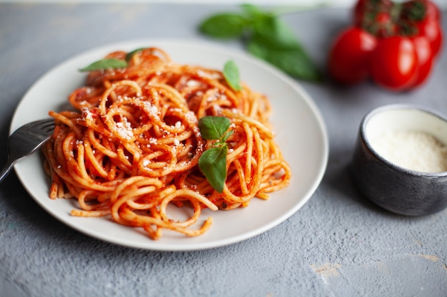 Tasty classic italian spaghetti with tomato sauce, parmesan and basil on plate