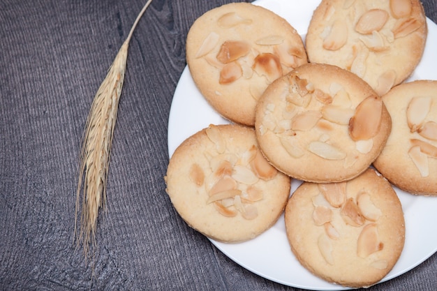 Tasty cookies biscuits with almond and wheat on the plate on wooden background. 