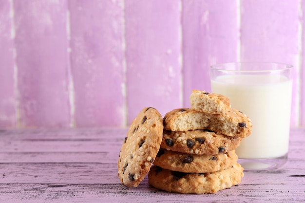 Tasty cookies and glass of milk on color wooden background