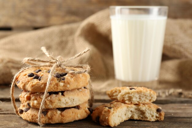 Tasty cookies and glass of milk on rustic wooden background