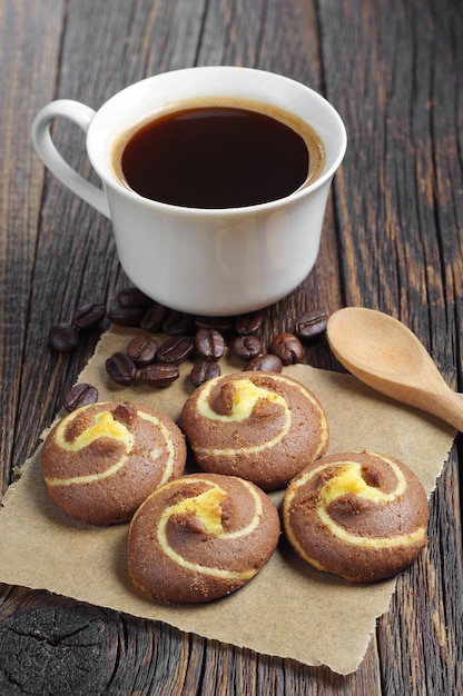 Tasty cookies with chocolate and cup of hot coffee on dark table