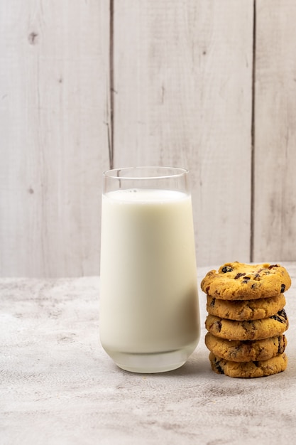 Tasty cookies with cramberries and glass of milk on table