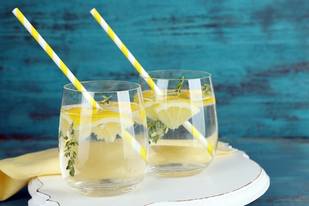 Tasty cool beverage with lemon and thyme on wooden background