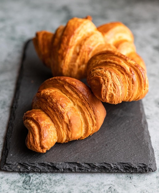 Tasty crispy croissants on black stone board grey background Homemade bakery for breakfast