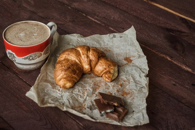 Photo tasty croissants with cup of coffee and chocolate on wooden table