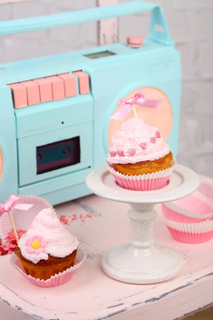 Tasty cup cakes with cream on wooden chair