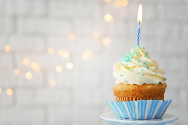 Tasty cupcake with candle on blurred background