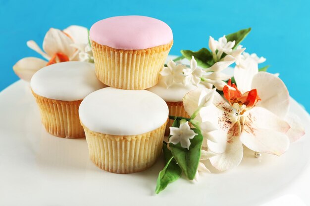 Tasty cupcakes on stand on color wooden background