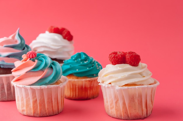 Tasty cupcakes sweets on pink background close up