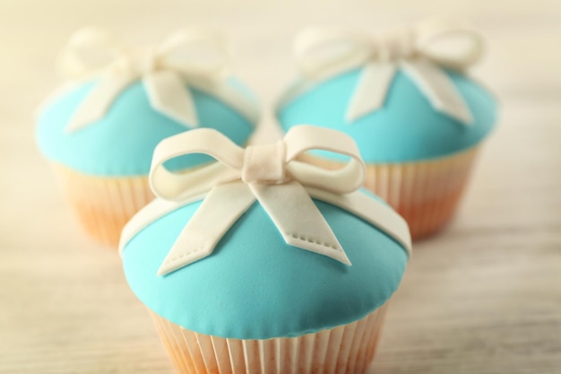 Tasty cupcakes with bow on light background