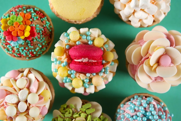 Tasty cupcakes with original decoration on turquoise background