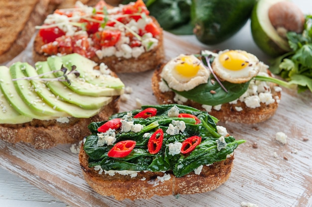 Tasty and delicious bruschetta with tomatoes, spinach, feta avocado red chili pepper and blue cheese. 