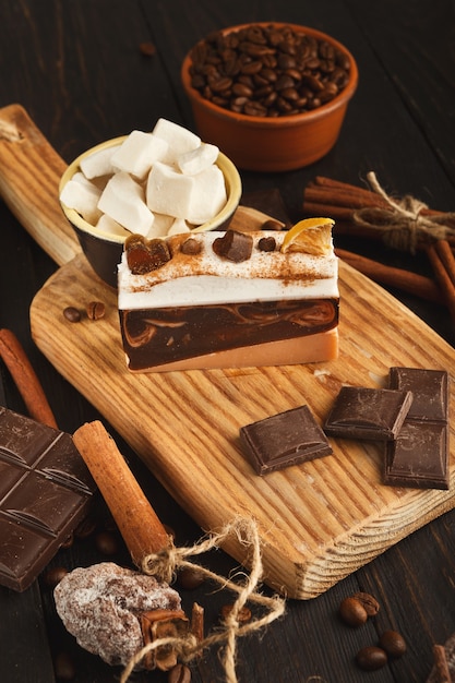 Tasty dessert background. Cake piece, chocolate bars, refined sugar, coffee beans, cinnamon and dry persimmon on rustic wooden table, side view. Advertizing design