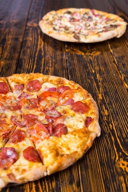 Tasty different pizzas with variety of toppings and cheese on wooden table