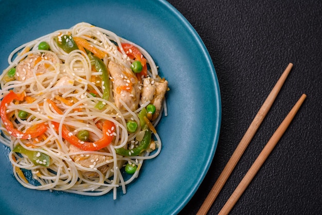 Tasty dish of Asian cuisine with rice noodles chicken asparagus pepper sesame seeds