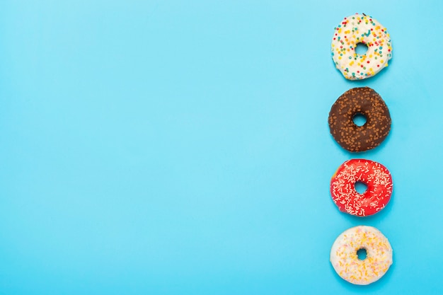 Tasty donuts of different types on a blue surface. Concept of sweets, bakery, pastries. . Flat lay, top view