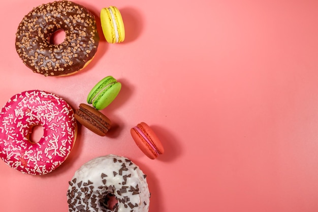 Tasty donuts and macaroons on pink background Top view copy space