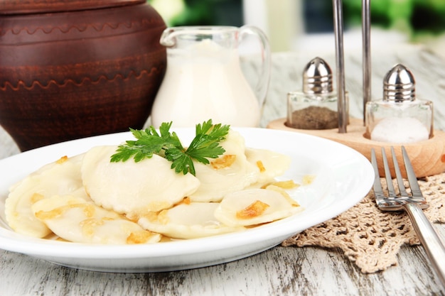 Tasty dumplings with fried onion on white plate on bright background