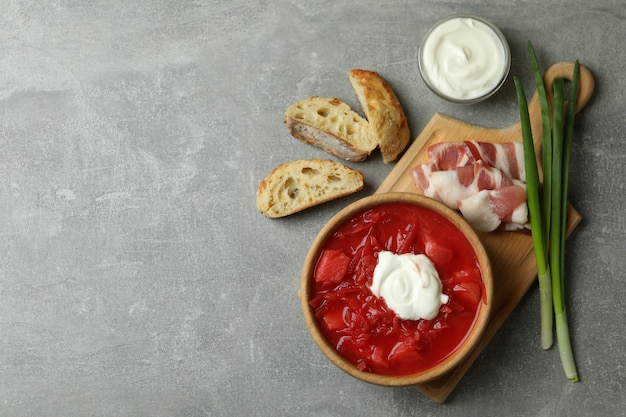 Tasty eating with borscht and ingredients on gray table