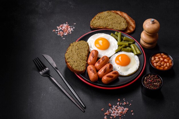 Tasty English breakfast of fried eggs beans asparagus sausages with spices and herbs