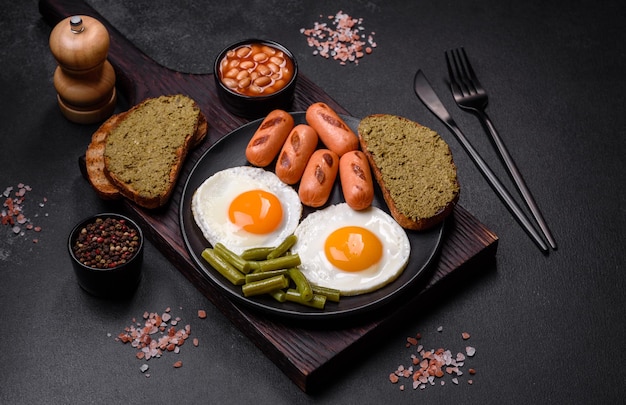 Tasty English breakfast of fried eggs beans asparagus sausages with spices and herbs