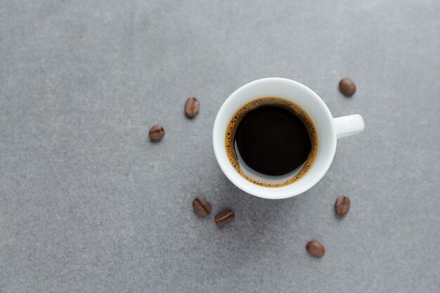 Tasty espresso in cup with coffee beans