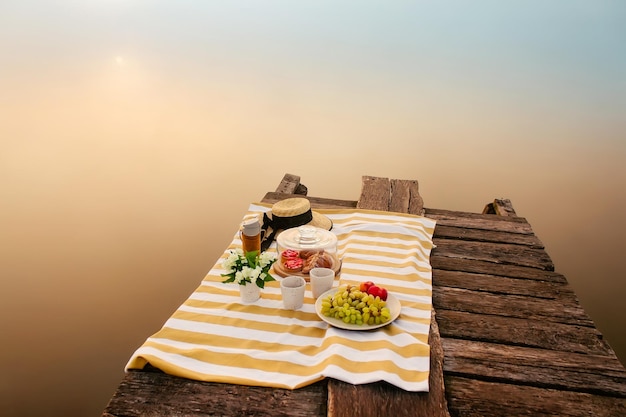 Tasty food for picnic outdoors near foggy lake at sunrise