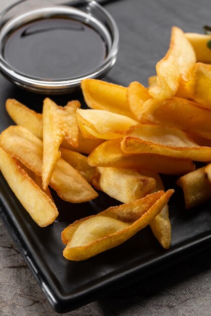 Tasty french fries on cutting board on wooden table background Top view flat lay