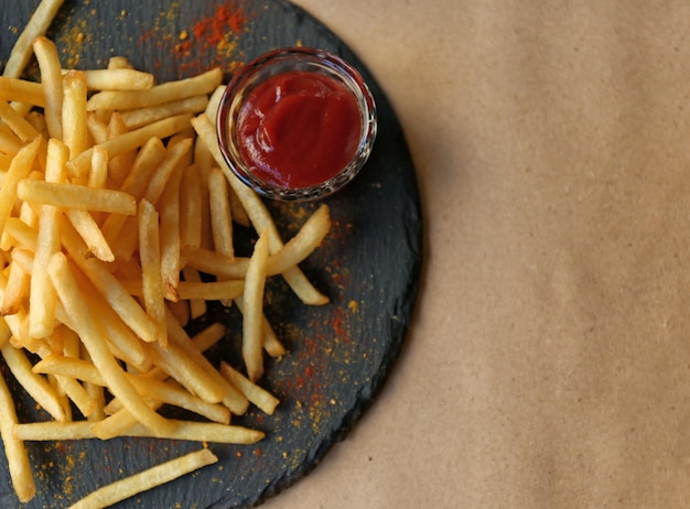 Tasty French fries with red sauce served on table in cafe top view Space for text