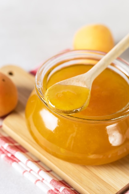 Tasty and Fresh Apricot Jam in a Glass Jar on Wooden Tray Napkin Wooden Spoon Above Vertical