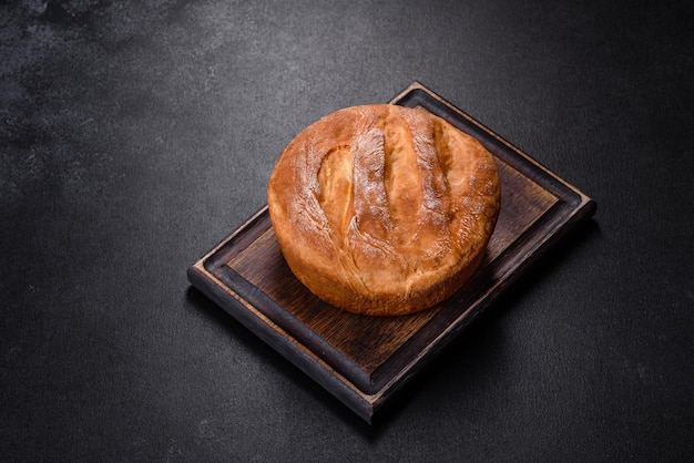 Tasty fresh baked in oven white bread on a dark concrete background