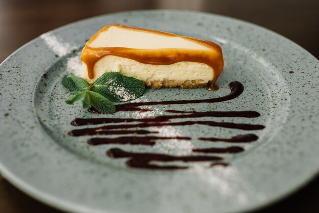 Tasty fresh cheesecake with chocolate, caramel and mint on plate