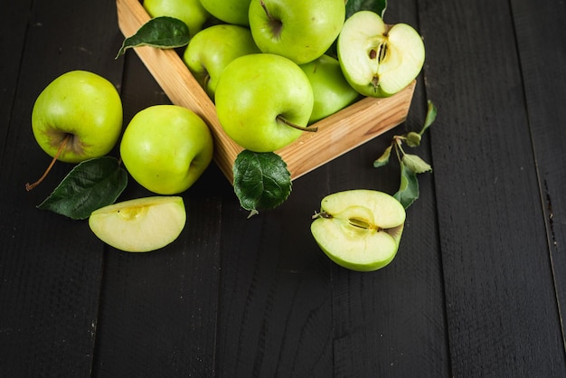 Tasty and fresh green apples in wooden box on the black wooden background. Top view. Copy space