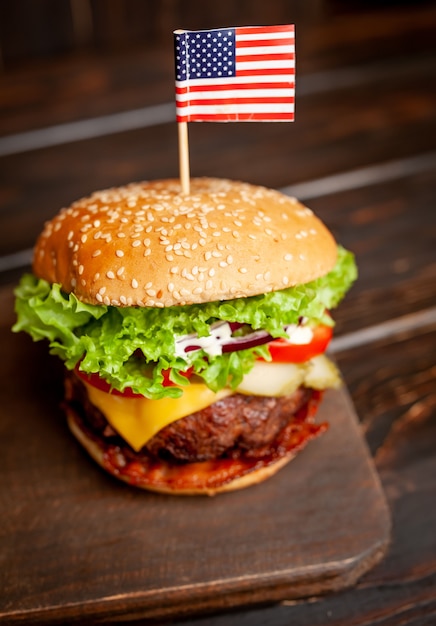 Tasty fresh homemade burger with american flag on wooden table