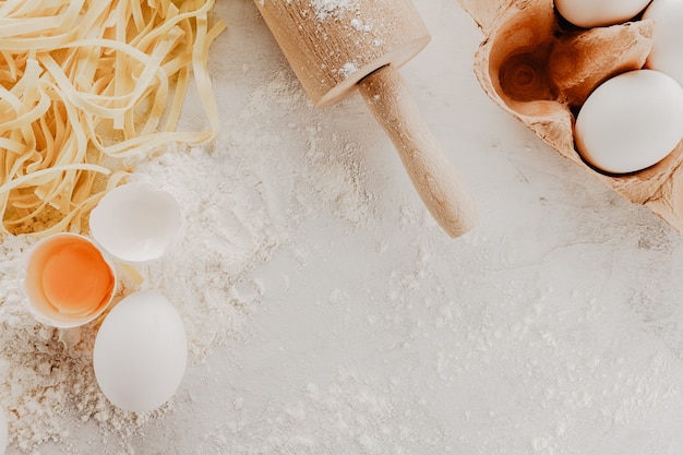 Tasty fresh raw pasta with flour and eggs on bright table