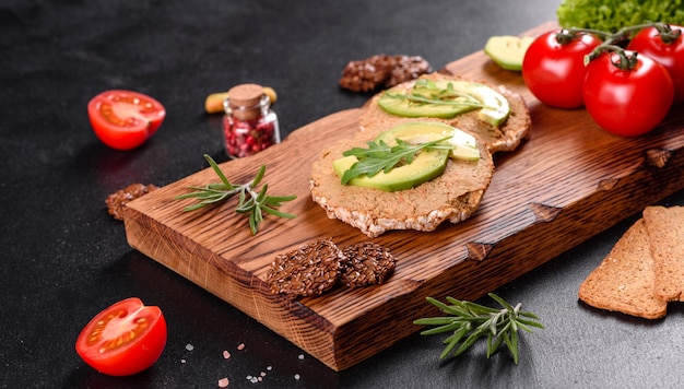 Tasty fresh sandwich with liver paste, avocado pieces and a arugula on a dark concrete table