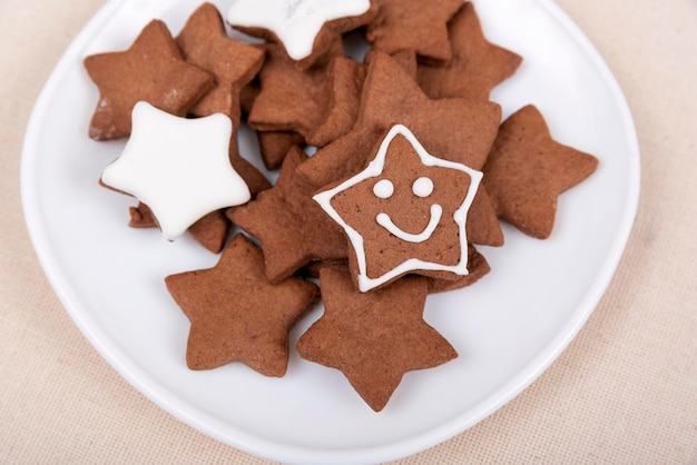 Tasty glazed painted cookies stars with smile on white plate Gingerbread cookie