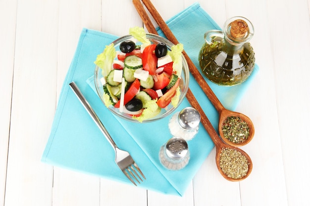 Tasty Greek salad with spices on white wooden background