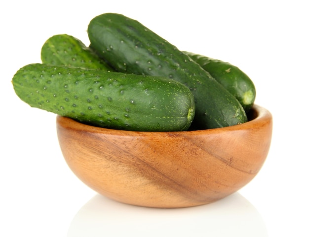 Tasty green cucumbers in wooden bowl, on white