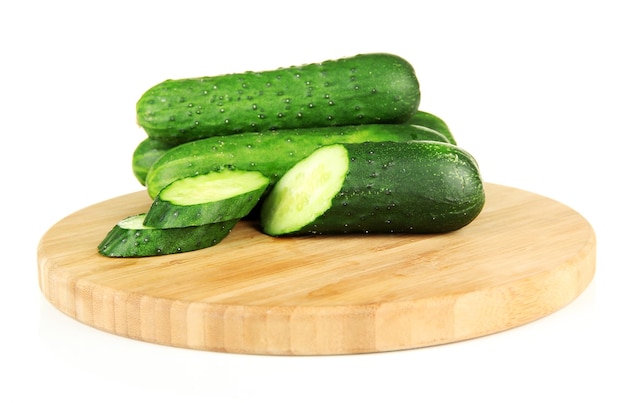 Tasty green cucumbers on wooden cutting board isolated on white