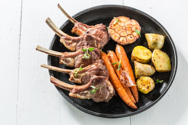 Tasty grilled ribs of lamb with vegetables on white table