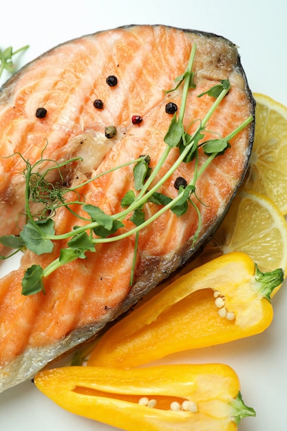 Tasty grilled salmon and ingredients on white background