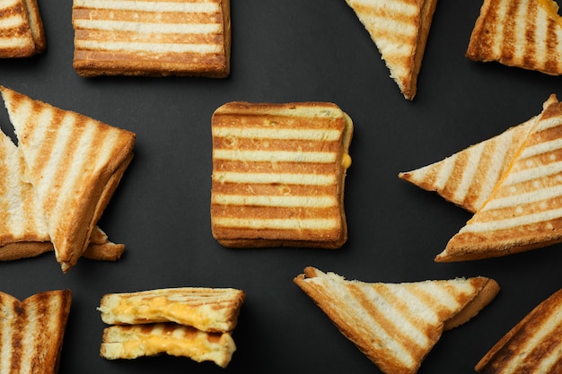 Tasty grilled sandwiches on black background, top view