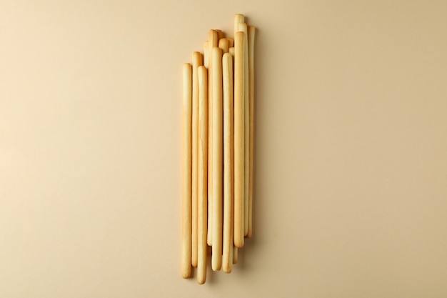 Tasty grissini breadsticks on beige, space for text