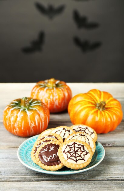 Tasty Halloween cookies on plate on wooden table