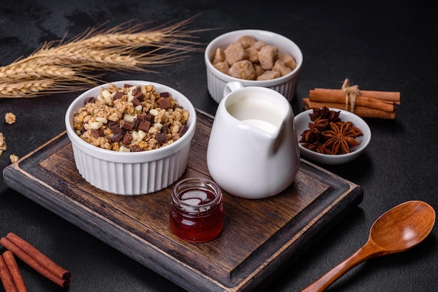 Tasty healthy breakfast with cereals granola chocolate milk and jam on a dark concrete background